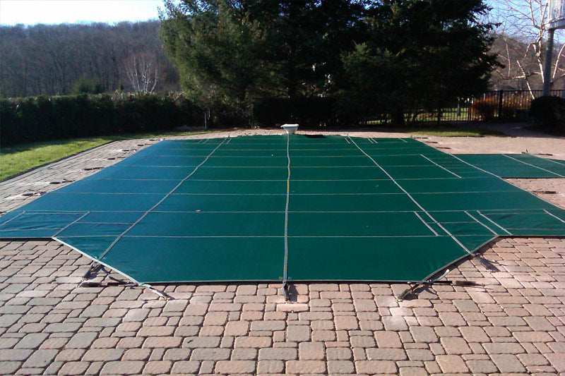 Green Pool Cover anchored to the ground on a sunny day